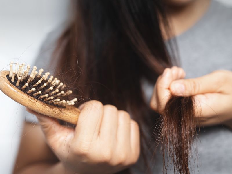 A woman with dry hair looking at the hair comb