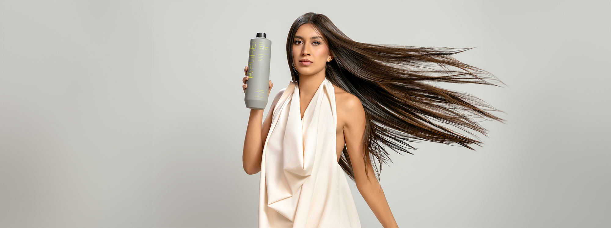 A lady with natural straight holding a bottle of Kpure hair care product