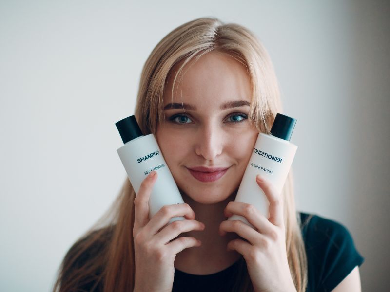 A lady holding shampoo and conditioner on her both hands