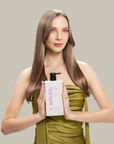 Woman holding a bottle of Kpure purple rain shampoo against a plain background